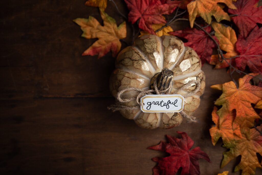 autumn table scape with small pumpkin and the word grateful on a decorative tag