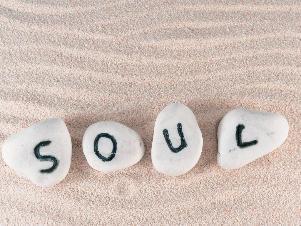 Rocks etched with the word Soul laying on sand